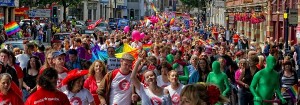 Street crowded with a parade of happy people with flags and balloons