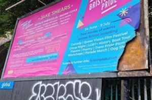 Large pink and blue billboard advertising Bristol Pride with bottom right corner charred by fire.