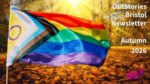 Multicoloured Pride flag fluttering against an autumnal forest clearing lit up by streaming sunshine